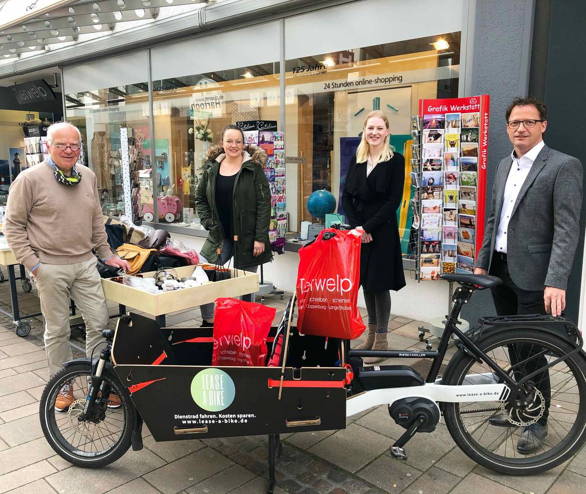 Four people with cargo bike in front of book shop Terwelp