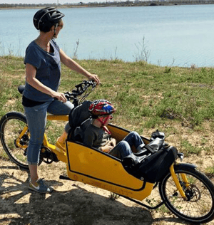 woman with kid in cargo bike in front of lake looking at it