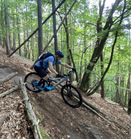 man riding mountainbike down the hill in forest bike leasing