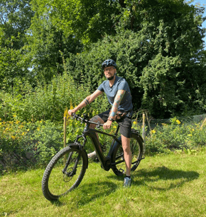 Mann auf Mountainbike in sommerlicher, grüner Landschaft