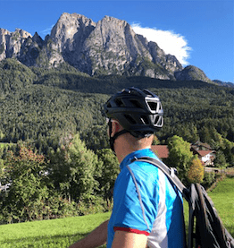 man with helmet and company bike looking at mountains