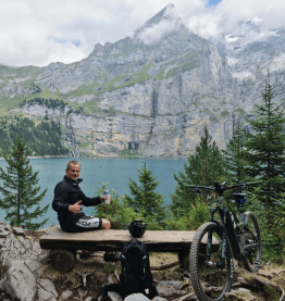 biker having a break in front of lake in mountains bike leasing