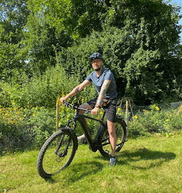 man sitting on bike in front of green landscape bike leasing