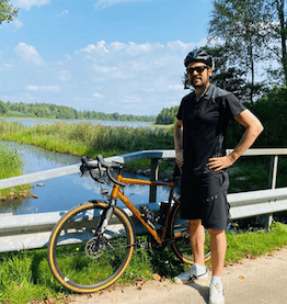 man standing next to bike on bridge in front of river bike leasing