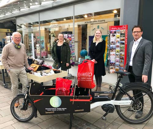 Four people with cargo bike in front of book shop Terwelp