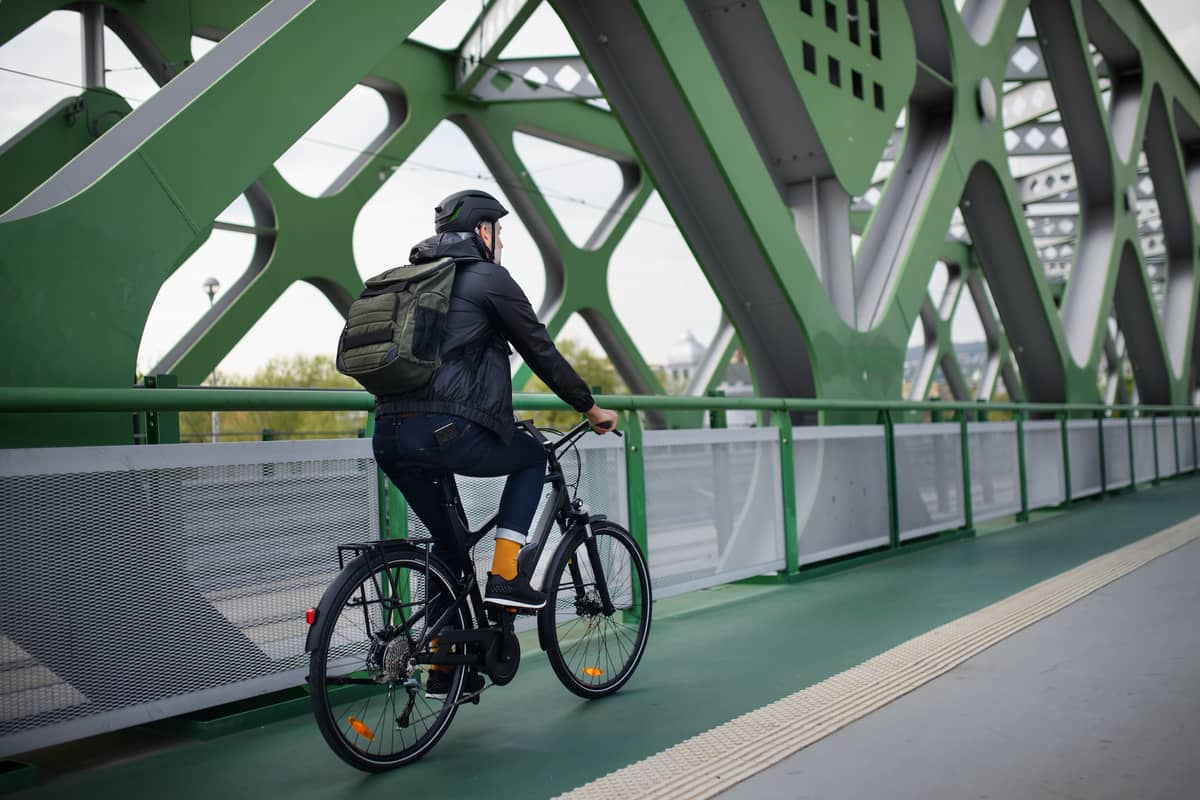 Mann mit Firmenfahrrad auf Brücke