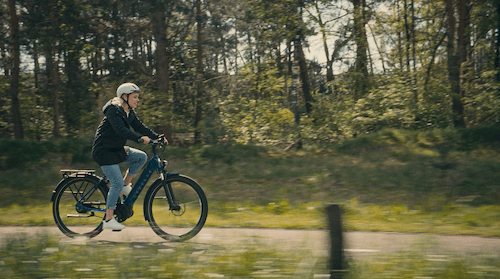 Frau fährt auf Fahrradweg in grüner Umgebung