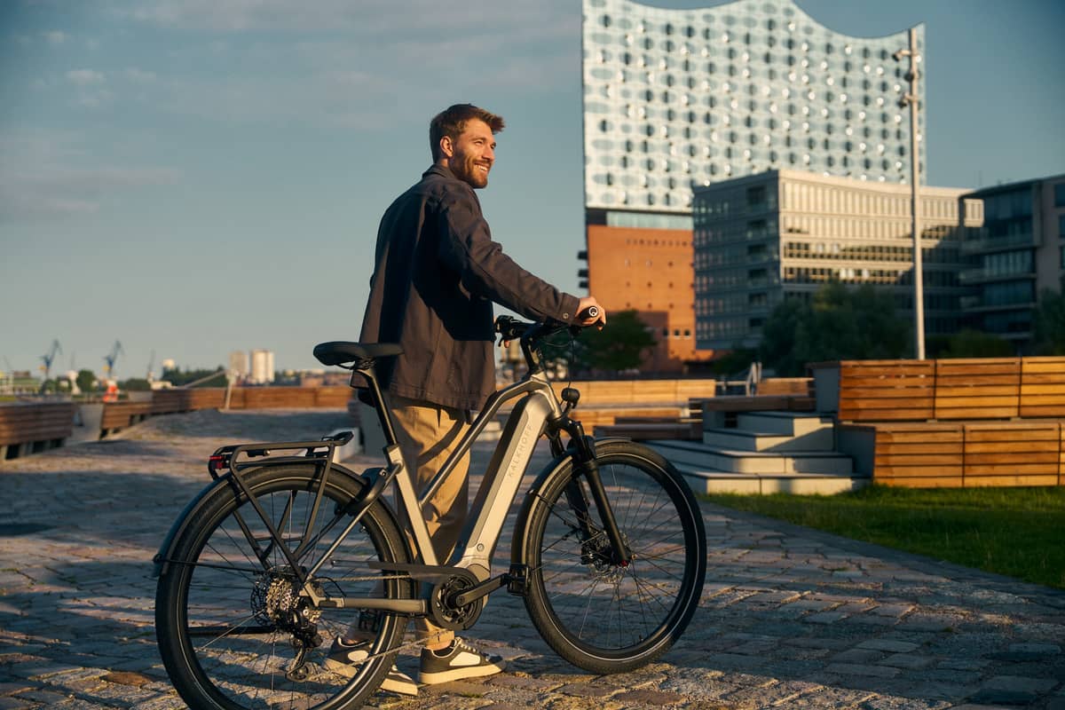 Nachhaltige Mobilität Kalkhoff Bikes Mann steht mit Fahrrad vor Elbphilharmonie