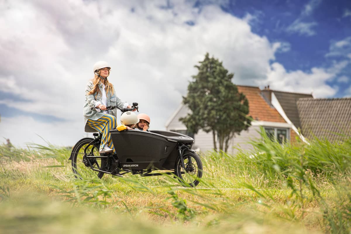 Frau mit zwei Kindern in Natur auf Lastenrad leasen