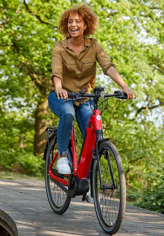 Woman on red Gazelle bike laughing and riding bike in nature